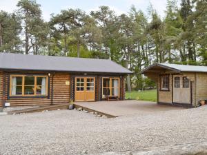 a log cabin with a porch and a garage at Ashknowe Log Cabin - S4590 in Glenfarg