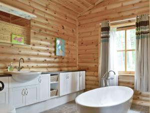 a wooden bathroom with a tub and a sink at Ashknowe Log Cabin - S4590 in Glenfarg