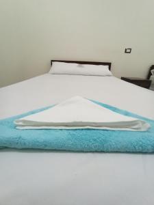 a white bed with a blue blanket on it at Al-Manara Hostel Siwa Oasis in Siwa