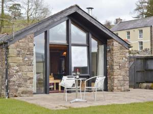 a stone cottage with a table and chairs on a patio at Y BWTHYN-oxm in Gwynfe