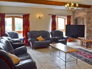 a living room with couches and a flat screen tv at The Stables in Somersal Herbert