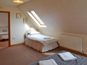 1 dormitorio con 1 cama con ventana y 2 toallas en The Stables, en Somersal Herbert