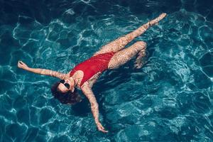 Una donna sdraiata sulla schiena in una piscina di Luxury room by Grand Vacations a Roches Noires