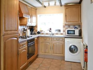 a kitchen with wooden cabinets and a washer and dryer at Holmlea in Beckfoot