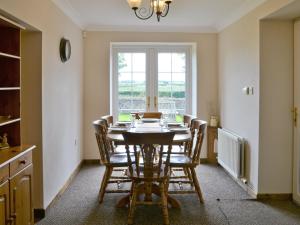 a dining room with a table and chairs and a window at Holmlea in Beckfoot