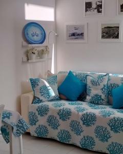 un sofá con almohadas azules y blancas en la sala de estar. en Villetta con Piscina e Campo da Tennis condominiale en Villasimius