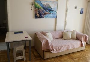 ein Sofa in einem Zimmer mit einem Tisch und einem Gemälde in der Unterkunft Όμορφο διαμέρισμα ρετιρέ 5ου ορόφου, στου Zografou in Athen