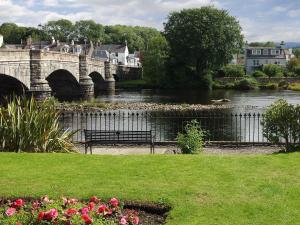 un banco junto a un río con un puente en Endeavours End, en Gatehouse of Fleet