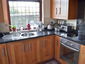 eine Küche mit Holzschränken, einem Waschbecken und einem Fenster in der Unterkunft Marstan House in Standish