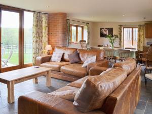 a living room with a leather couch and a table at The Old Workshop in Alderminster