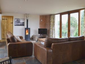 a living room with two leather couches and a television at The Old Workshop in Alderminster