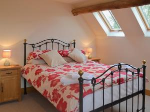 a bedroom with a bed with a red and white bedspread at The Old Workshop in Alderminster