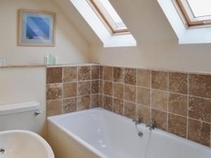 a bathroom with a bath tub and a sink at The Old Workshop in Alderminster