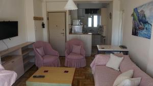 sala de estar con 2 sillas rosas y sofá en Όμορφο διαμέρισμα ρετιρέ 5ου ορόφου, στου Zografou, en Atenas