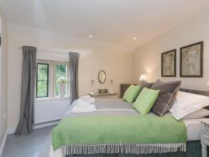 a bedroom with a large bed with green pillows at Hall Cottage in Brampton