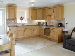 a kitchen with wooden cabinets and a table and a couch at No 2 Pegraig Draw - Uk6435 in Llanychaiarn
