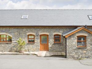 uma casa de pedra com uma porta castanha e janelas em No 2 Pegraig Draw - Uk6435 em Llanychaiarn