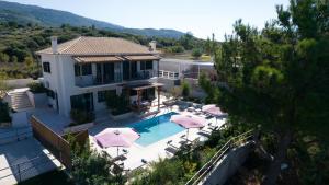 a house with a swimming pool with umbrellas at Villa Endless Blue in Kalamitsi