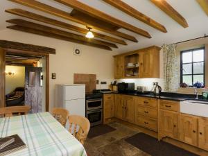eine Küche mit Holzschränken und einem Tisch mit Tischdecke in der Unterkunft Highbury Cottage in Hathersage
