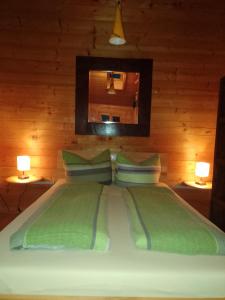 ein Bett mit zwei grünen Kissen und einem Spiegel in der Unterkunft Hüttenzauber Ferienwohnung mitten im Nationalpark in Lindberg