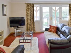 a living room with a leather couch and a tv at River Lodge in Polperro