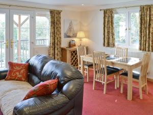 a living room with a leather couch and a table at River Lodge in Polperro