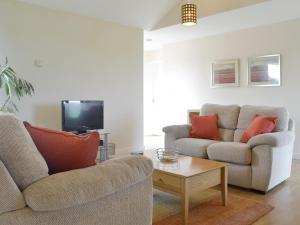 a living room with two couches and a tv at Bramley Cottage in Brean