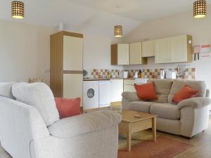 a living room with two couches and a kitchen at Bramley Cottage in Brean