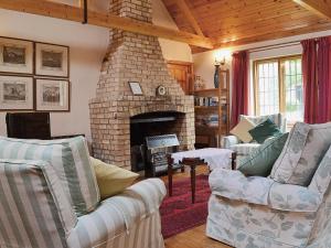a living room with a stone fireplace with two couches at Netherall Manor Lodge in Soham