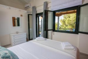 a bedroom with a white bed and a window at Villa Endless Blue in Kalamitsi