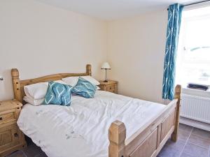 a bedroom with a bed with blue and white pillows at Smithy Barn - Hw7592 in Bettws-yn-Rhôs