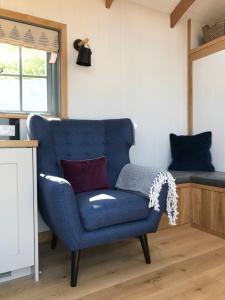 een blauwe stoel in een kamer met een bed bij Skylark Shepherds Hut in Bath