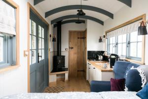 a bedroom with a blue door and a kitchen with a stove at Skylark Shepherds Hut in Bath