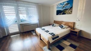 a bedroom with a bed and two large windows at Apartamenty w Maniowach in Maniowy