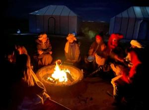 Un groupe de gens assis autour d'un feu dans l'établissement BerberNightCamp, à Adrouine