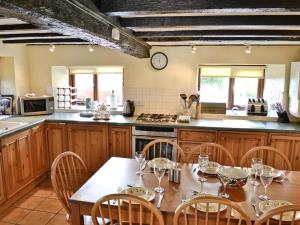 a kitchen with wooden cabinets and a table with chairs at 1 Oaks Farm Cottages in Ambleside