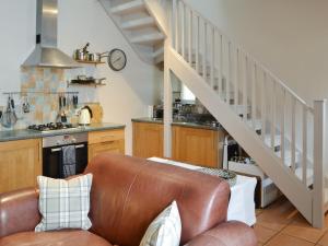 a living room with a leather couch and a staircase at Youngers Cottage in Warkworth