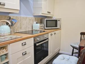 a small kitchen with a stove and a microwave at Granary Cottage in Torquay