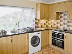 a kitchen with a washing machine and a sink at Salfur in Rhiw