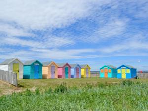 una fila de coloridas cabañas de playa en un campo en Sea Breeze, en Amble