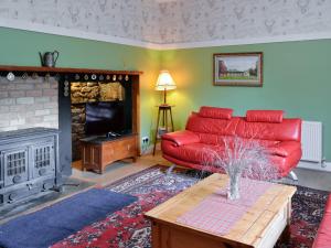 a living room with a red couch and a fireplace at The Mews in Insch