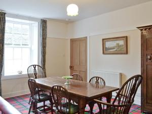 a dining room with a wooden table and chairs at The Mews in Insch