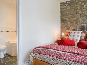 a bedroom with a bed and a stone wall at Yr Ysgubor in Sarnau