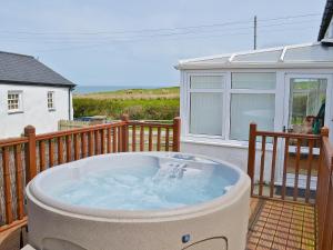 a hot tub on the deck of a house at Porth Cormon Farmhouse in Llangwnadl