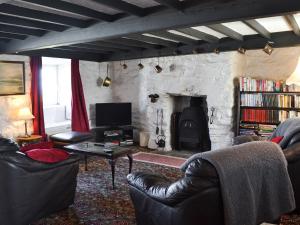 a living room with leather furniture and a stone fireplace at Porth Cormon Farmhouse in Llangwnadl