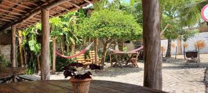 un patio al aire libre con mesa, sillas y hamacas en Casinhas Vila Bonita Amarela, en Baía Formosa