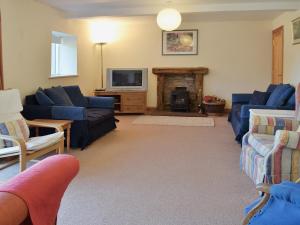 a living room with blue couches and a fireplace at Fenham Barn in Soulby