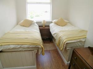 two beds in a small room with a window at Lobster Cottage in Flamborough
