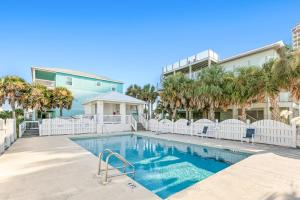 a swimming pool in front of a building with palm trees at Beachy Dreams in Pensacola Beach