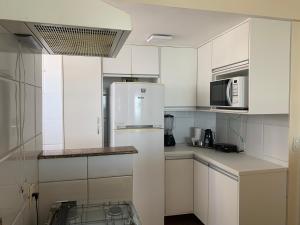 uma cozinha com armários brancos e um frigorífico em Porto Marina 1 em Salvador